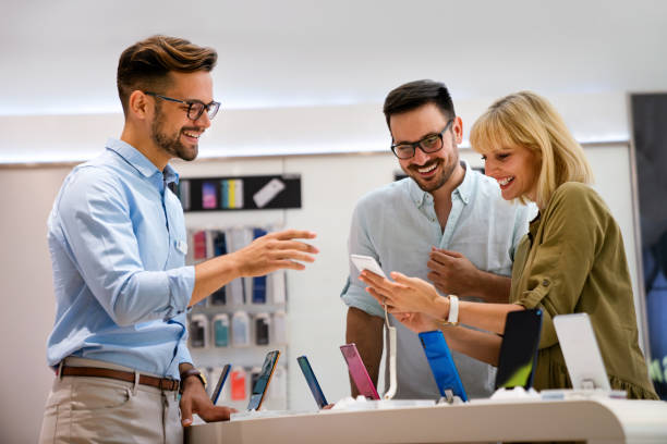 Portrait of salesman helping to couple to buy a new digital device in tech shop. Technology people concept